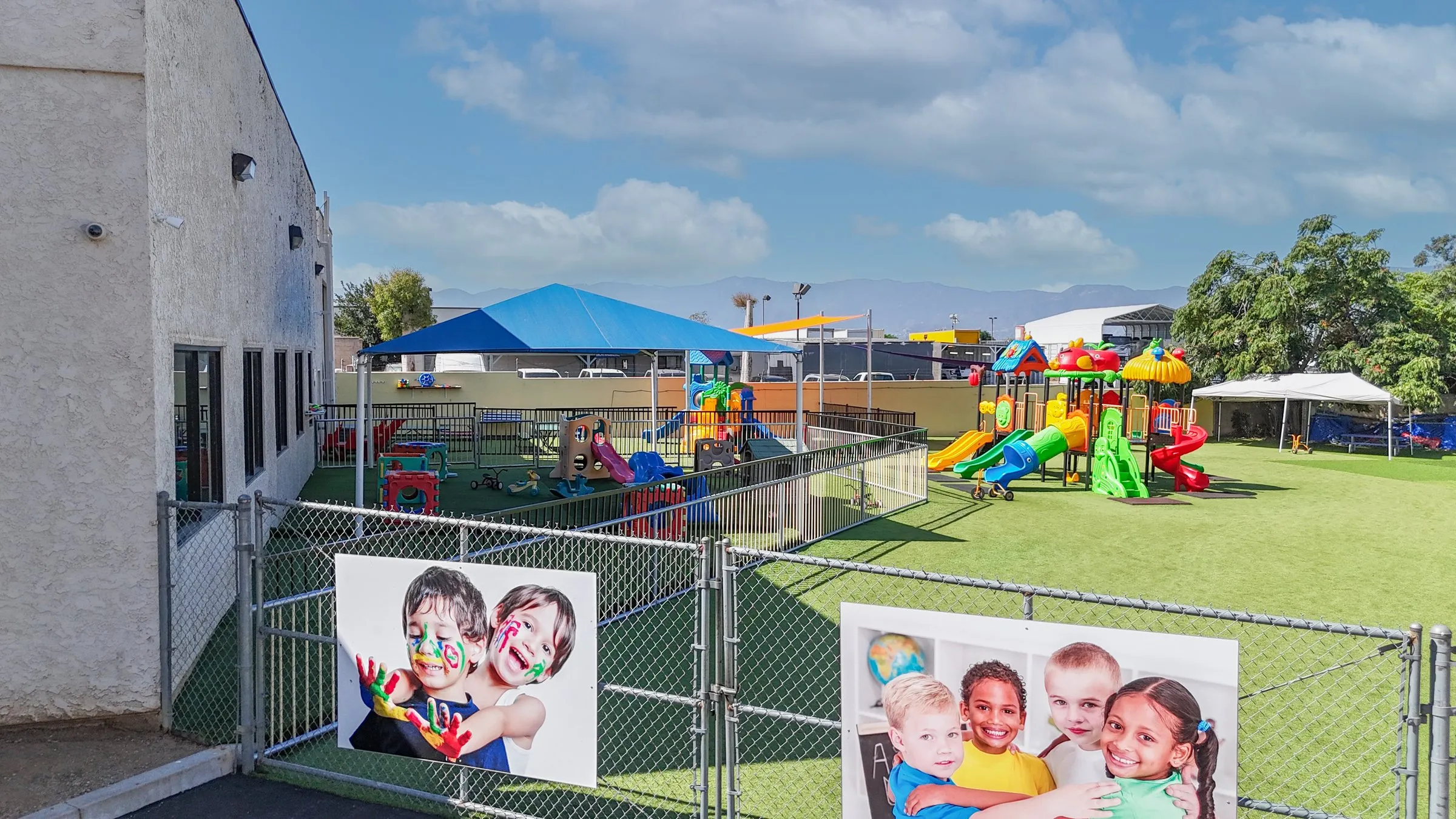 The fenced outdoor play yard with a blue shade canopy and a second play structure.